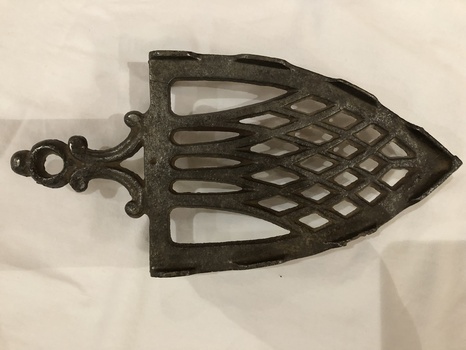 A decorative cast iron trivet for a vintage flat iron.