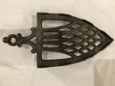 A decorative cast iron trivet for a vintage flat iron.