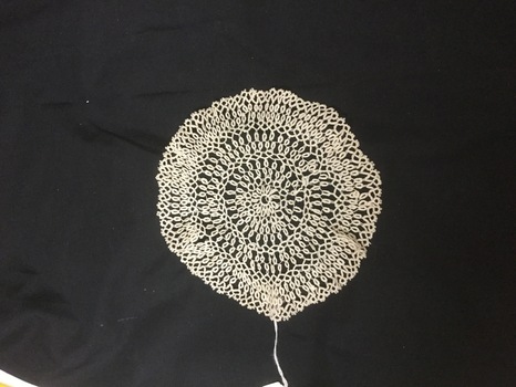 White lacy doily on black background.