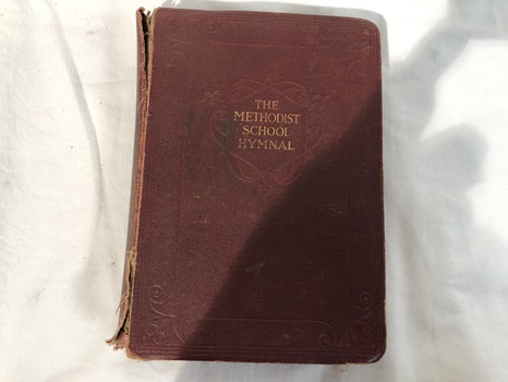 A damaged vintage red leather bound Methodist School Hymnal Book. 