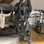 Cast iron grain sickle with hand-cranked wooden handle, stone grinder head, and 4 wheels, on a wooden base.