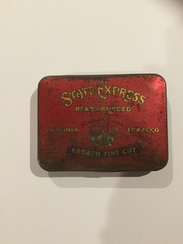 A red rectangular, State Express tobacco tin with a hinged lid. 