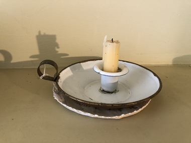 A white enamel candlestick holder with gold metallic paint on the outside surface. 