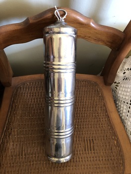 A stainless steel, cylindrical bed warmer, with a removable screw stopper which has a looped handle on top. 