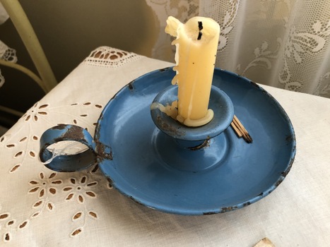A sky blue candlestick holder used by carrying around the home.