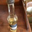 A tall clear glass bottle half filled with Castor Oil for medicinal purposes. It has a rusted metal screw top lid and a label for use.