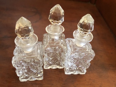 Three small cut glass perfume bottles with ground glass stoppers.