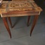 A highly decorative wooden music box table with colourful inlaid wood on the lid and sides and inside is a recessed wooden box.