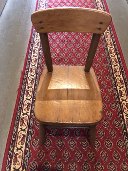 A small lacquered wooden  kindergarten chair with a seat, backrest, four legs and two side supports for the backrest.
