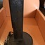 A rusty metal Designoscope or kaleidoscope with a long triangular tube connected to a flat stand at the bottom.
