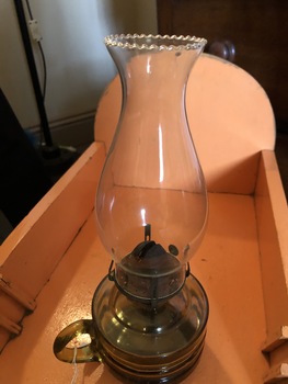 An amber coloured oil lamp with a clear glass chimney.
