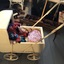 A vintage cream painted wooden and metal dolls pram with a hood, four wheels and a tubular long push curved handle. 