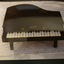 A black painted wooden 'Pixiano Major' toy piano in a baby grand shape with 20 keys, a lift up lid and three legs.