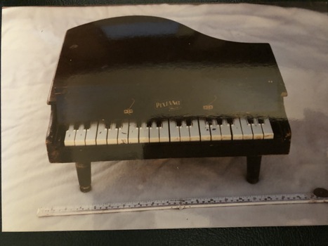 A black painted wooden 'Pixiano Major' toy piano in a baby grand shape with 20 keys, a lift up lid and three legs.