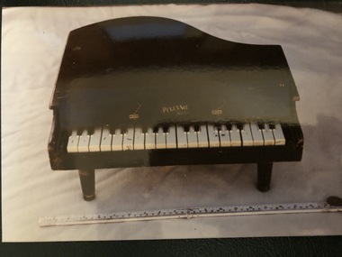 A black painted wooden 'Pixiano Major' toy piano in a baby grand shape with 20 keys, a lift up lid and three legs.