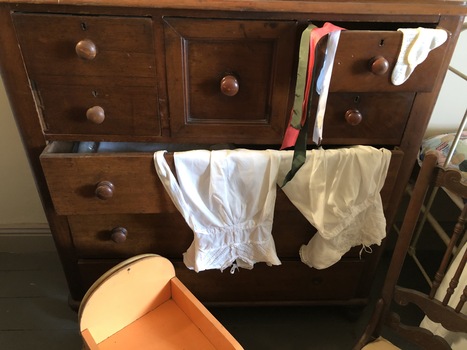 A brown wooden chest of eight drawers with a turned knob to open them.