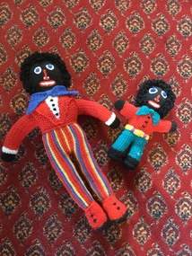 Two woollen knitted golliwogs with bight coloured clothes, black faces, hands, feet and hair.