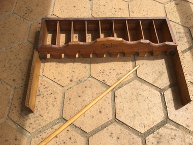  Handmade wooden table game has nine numbered holes at the bottom and slots behind and a wooden cue stick. 