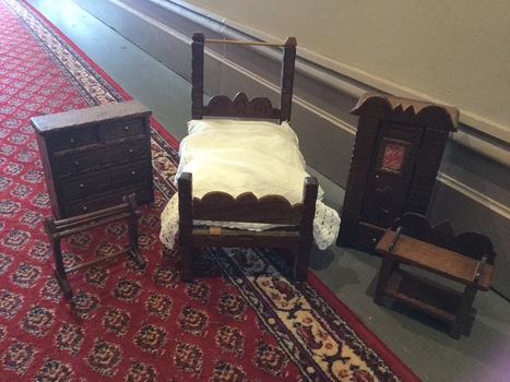 Five pieces of highly decorated wooden doll's furniture: washstand, bed, wardrobe, chest of drawers, towel rail and clothes dryer.