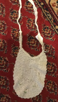 Two white baby bibs; one is crotcheted and the other is made of cotton with embroidery of two ladies wearing bonnets.