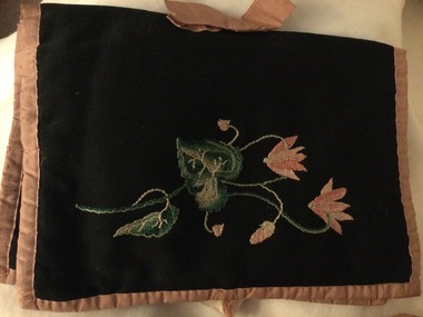 A black cotton embroidered pouch or hold all which has an apron and various small sachets inside.