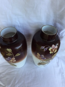 A pair of cream and brown vases painted with flowers and leaves.