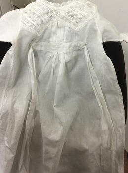 A white child's nightgown with lace trimming and ties.