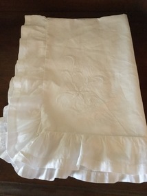 A large white embroidered cotton pillowcase with a wide frill.