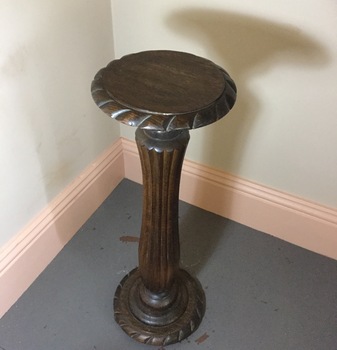 A wooden carved pedestal with barley sugar edging on the top and base.