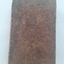 An antique brown marbled hardcover book of the New Testament in French with no title printed on the cover. 