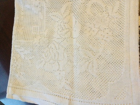 A white rectangular lace tablecloth, with floral and rectangular lace or crotchet style overall pattern.