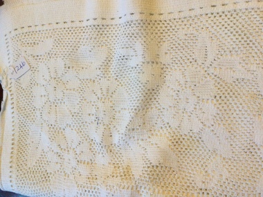 White rectangular lace tablecloth, with a floral pattern and a rectangle shape in the centre with an oval floral design.
