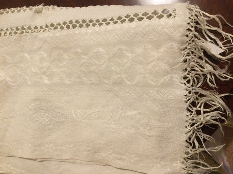 A long white patterned cotton table runner, which has two lines of open stitched pattern down the middle.