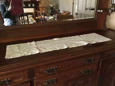 A long white cotton embroidered table runner with a floral pattern.
