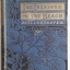 A blue hardcover book with the title The Treasure on the Beach in a gold boxa t the top of the cover. The word Illustrated is in gold lettering below. A black floral pattern  covers the book.