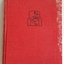 A red fabric covered hardcover novel with a black outline of a boy sitting on a couch reading a book.