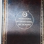 A maroon leather covered International Dictionary Australasian Edition with gold lettering for the title on the front cover. Has A-M written in small gold letters down the right side of the cover which is detached from the spine.