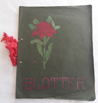A homemade blotter for writing use with a green cover and tied with a red ribbon. 