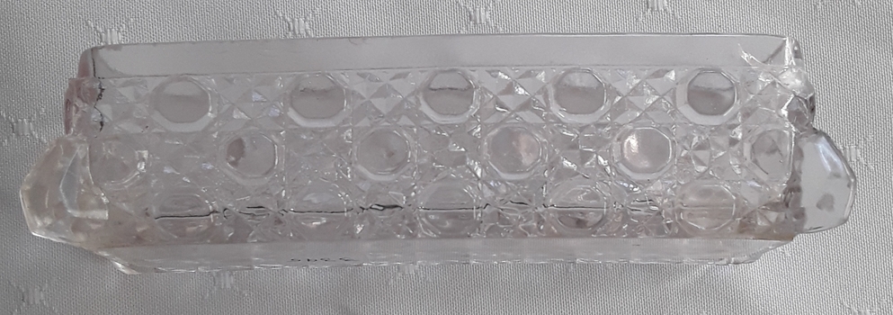 A small narrow Windsor cut clear glass container used in the bedroom.
