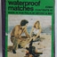 A matchbox and waterproof safety matches with a picture of two people near a fire on the beach.