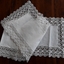A long white floral patterned lace embroidered edged cotton table runner for a table or sideboard.