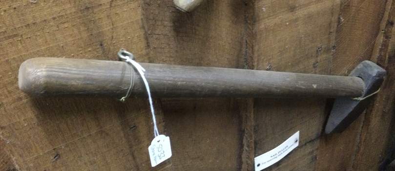A wooden handled hammer with a turned steel forged head possibly used for stone breaking.