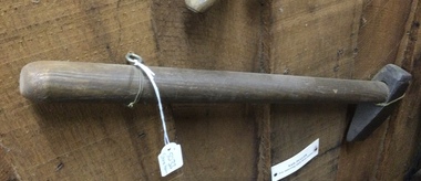 A wooden handled hammer with a turned steel forged head possibly used for stone breaking.