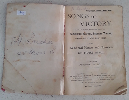 A red covered book of hymns and solos for religious gatherings.