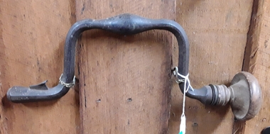 A steel bit brace with a wooden knob on the end of the turning handle.