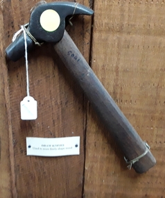 A small steel headed hammer with a wooden handle, possibly used by a cobbler.