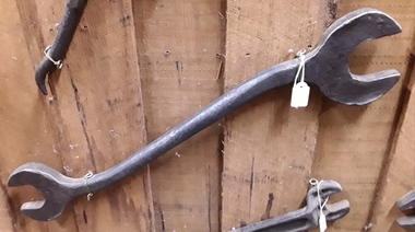 A medium sized steel double headed spanner used to tighten nuts on a plough.