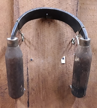 A steel curved bladed tool with two wooden handles used to shave wood.