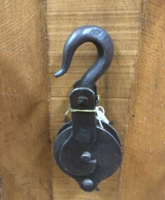 An antique forged steel pulley block and hook.