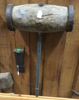 A large wooden barrelled metal handled maul and splitting wedge used in the 19th century.